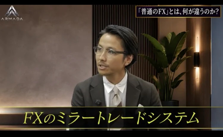 スーツ姿の男性が話す動画の場面に「FXのミラートレードシステム」という字幕が入っている