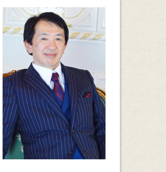 ロジャー堀のプロフィール写真。スーツ姿の男性が椅子に座っている広告画面